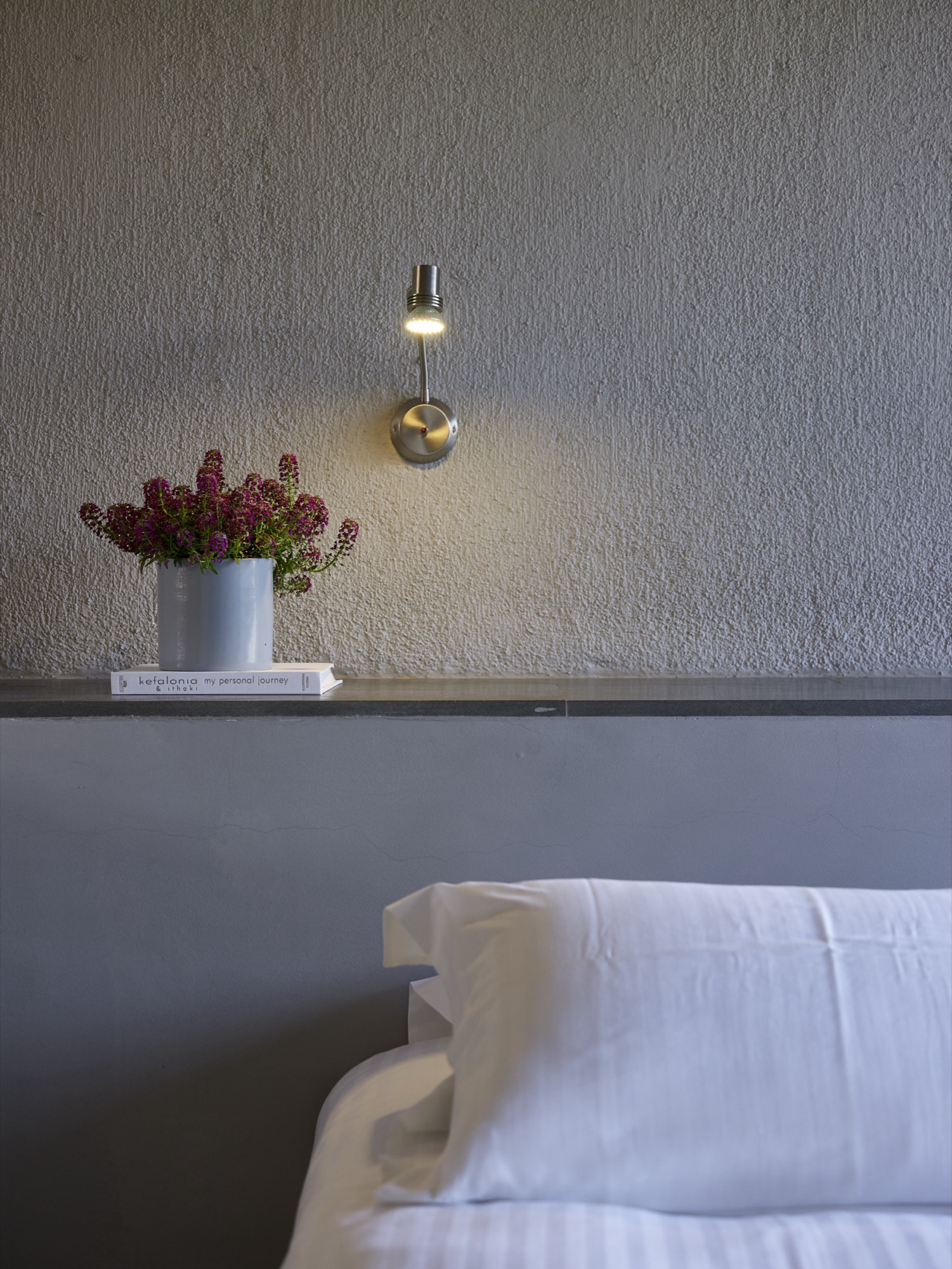 Reading lamp, bedside flowers, and crisp linen