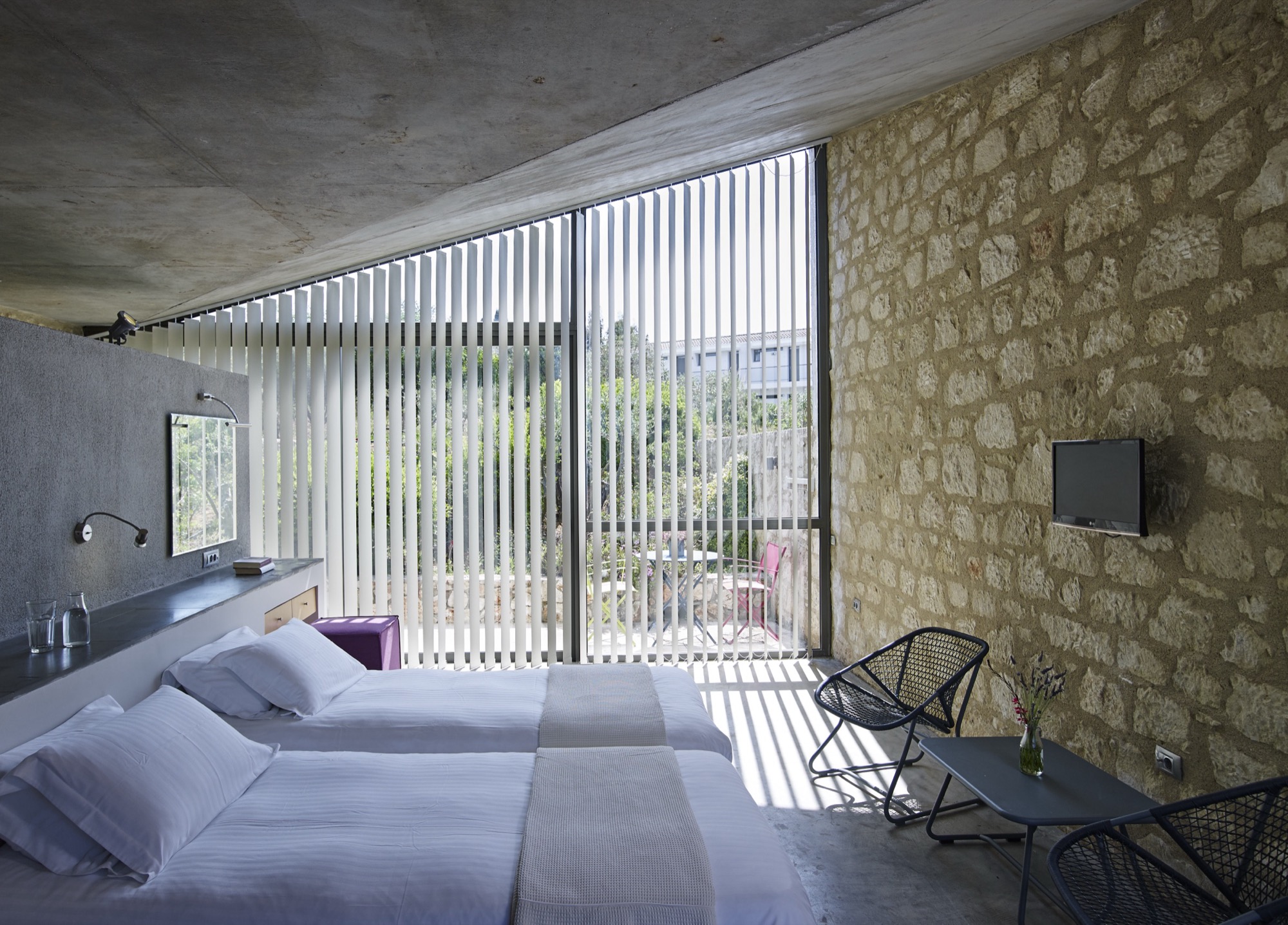 Bedroom with stone wall and louvered window onto the garden